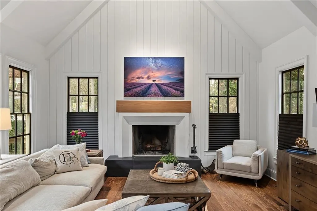 Living room featuring lofted ceiling, wood finished floors, and a fireplace with raised hearth