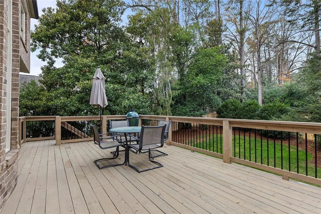 Deck with outdoor dining area, grilling area, and view of wooded area