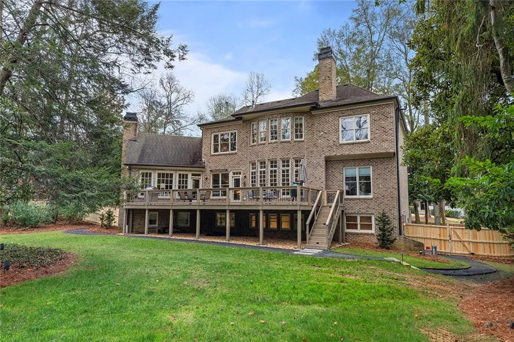 Rear view of property featuring a chimney, a deck, stairs, and brick siding