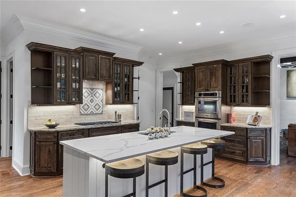 Kitchen featuring open shelves, glass insert cabinets, dark brown cabinetry, a breakfast bar, and crown molding