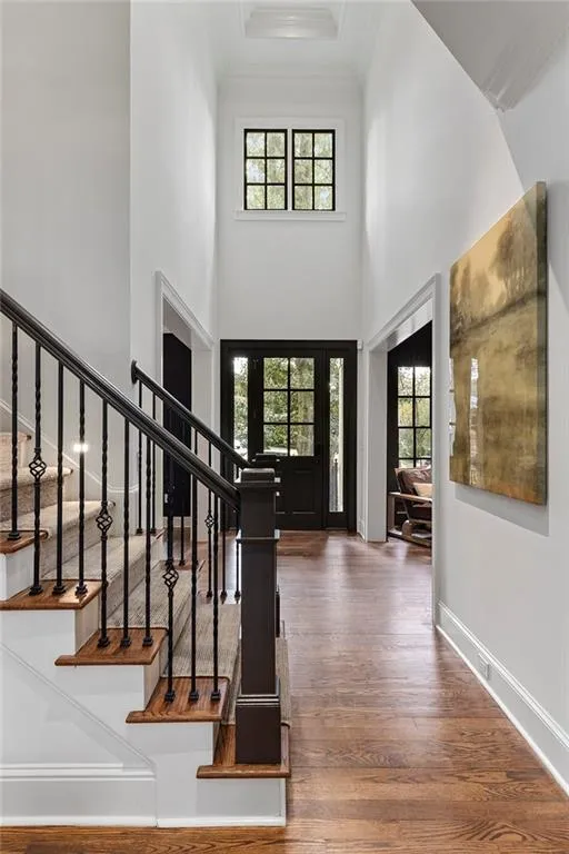 Foyer entrance featuring wood-type flooring, crown molding, and a high ceiling