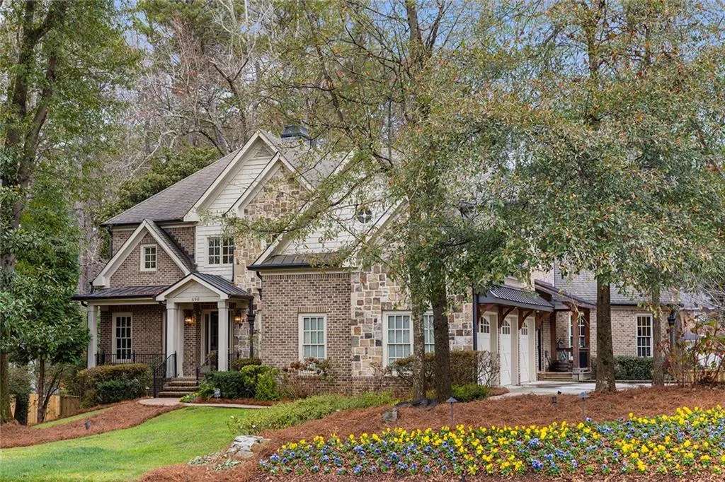 View of front of house with a standing seam roof, stone siding, a metal roof, a garage, and roof with shingles