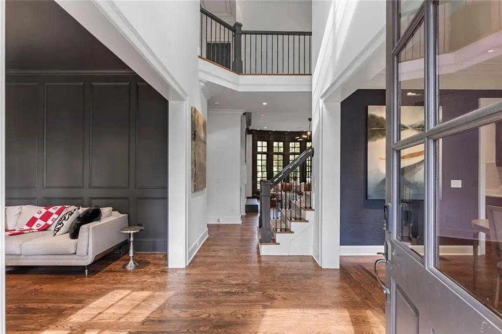 Foyer entrance with a decorative wall, wood finished floors, a towering ceiling, and stairway