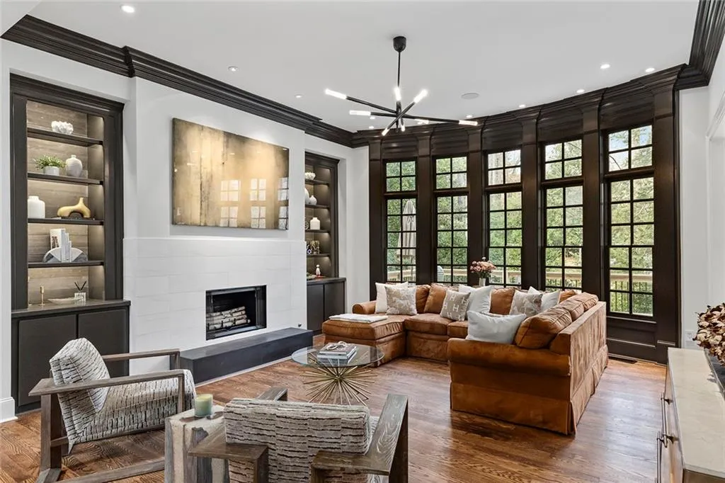 Living area with built in features, a fireplace, crown molding, a chandelier, and wood finished floors