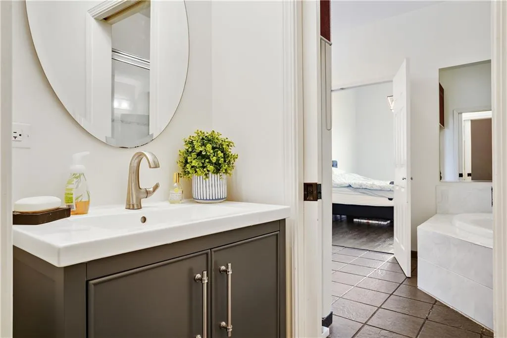 Ensuite bathroom featuring vanity, a bath, and dark tile patterned flooring