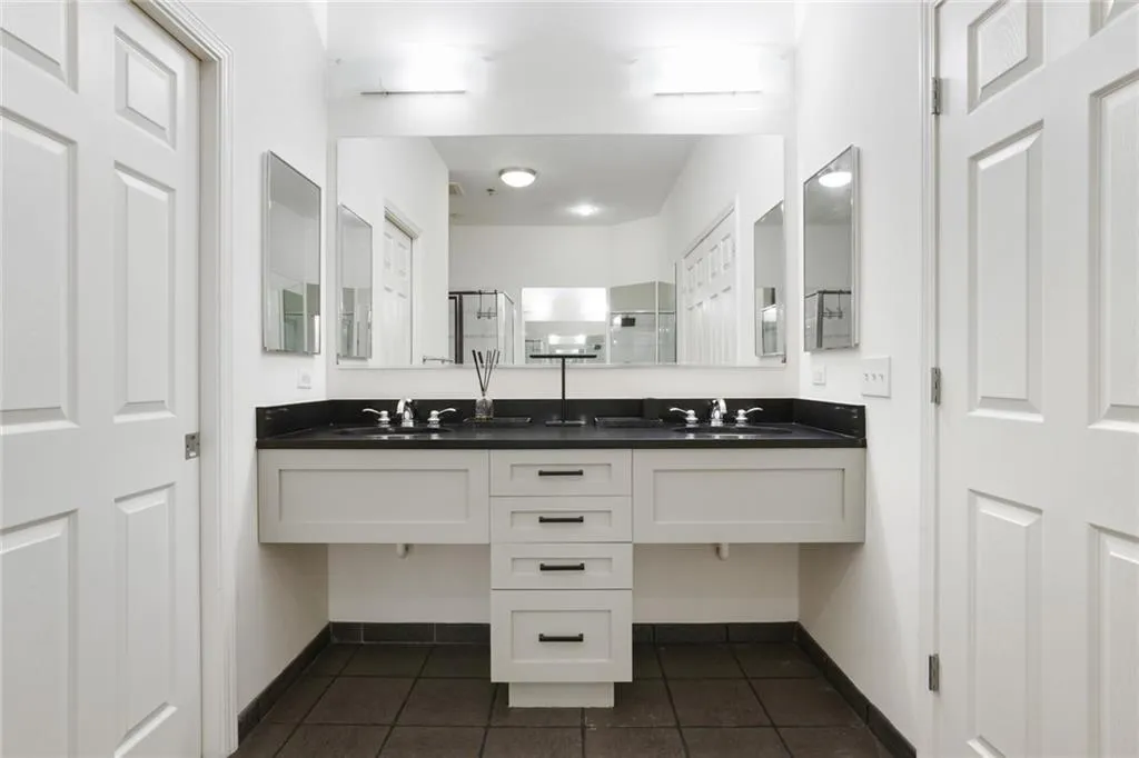 Full bathroom with a shower stall, dark tile patterned floors, and double vanity