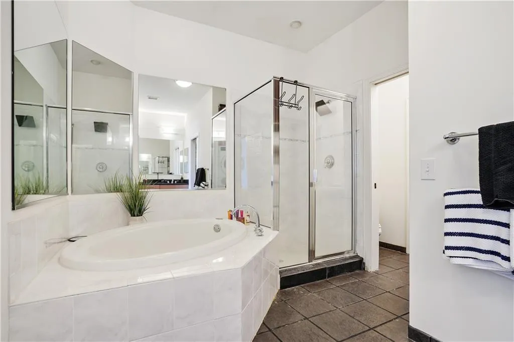 Bathroom with a stall shower, a garden tub, and dark tile patterned flooring