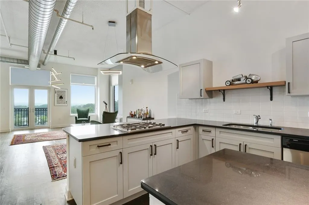 Kitchen with island exhaust hood, backsplash, hanging light fixtures, stainless steel appliances, and open floor plan