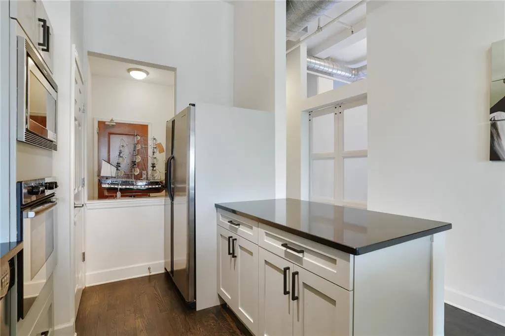Kitchen featuring dark wood-style flooring, white cabinets, and appliances with stainless steel finishes
