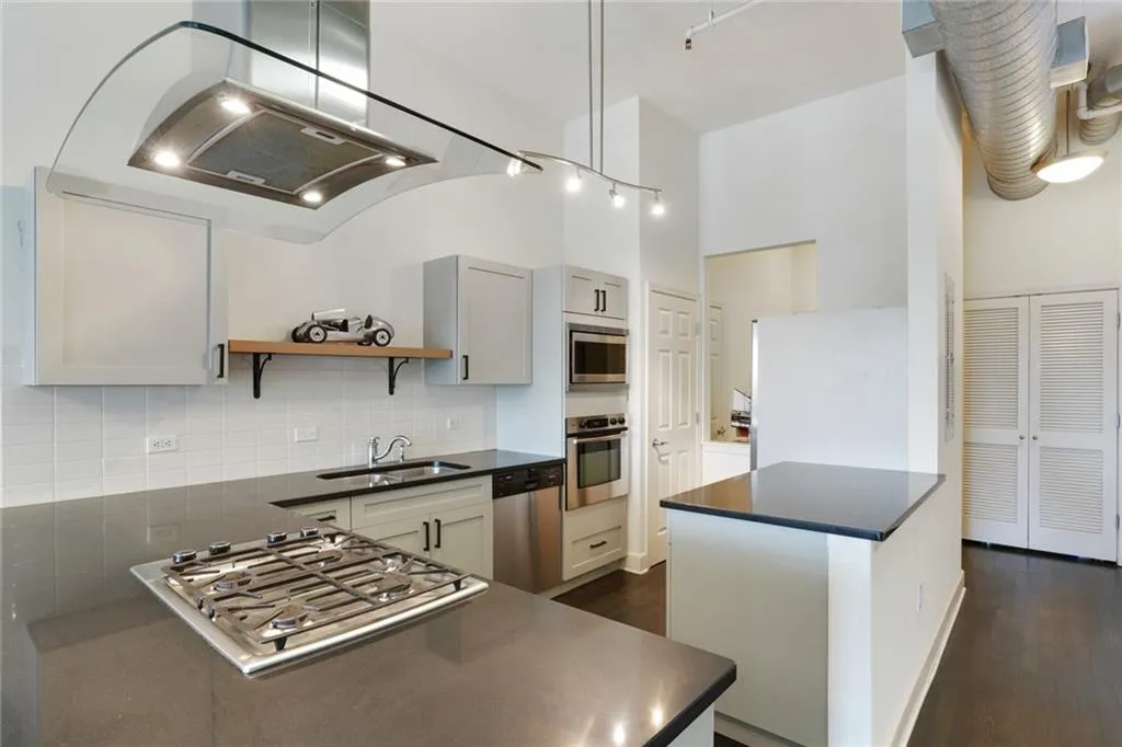 Kitchen featuring decorative backsplash, dark wood-style flooring, extractor fan, appliances with stainless steel finishes, and open shelves