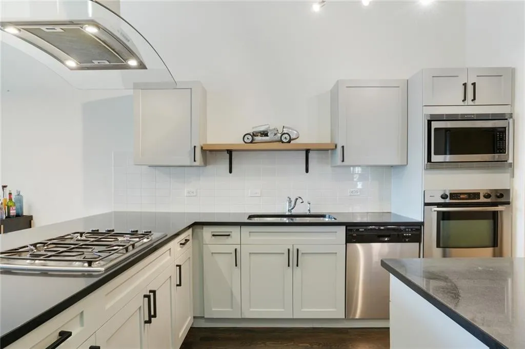 Kitchen featuring appliances with stainless steel finishes, ventilation hood, open shelves, tasteful backsplash, and dark wood-style flooring