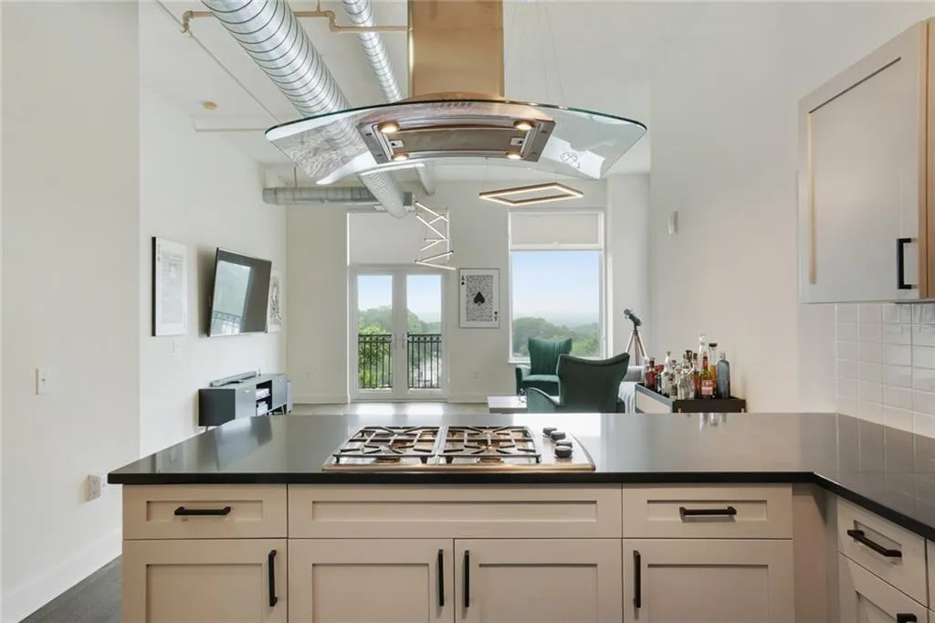 Kitchen featuring island range hood, open floor plan, stainless steel gas cooktop, a peninsula, and decorative backsplash