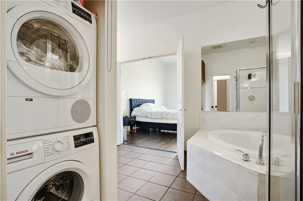 Laundry room featuring stacked washer / dryer and light tile patterned floors