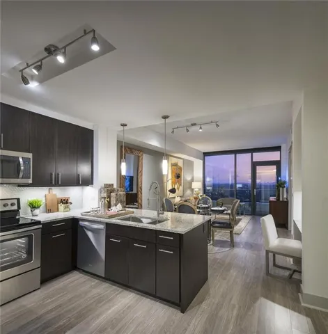 Kitchen with kitchen peninsula, backsplash, track lighting, sink, and appliances with stainless steel finishes