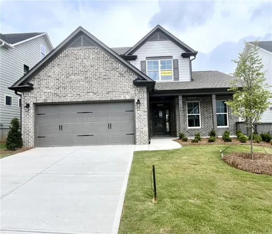 Brick and siding exterior featuring a two-car garage with decorative hardware, a covered front entry with columns, a concrete driveway, and a landscaped front yard