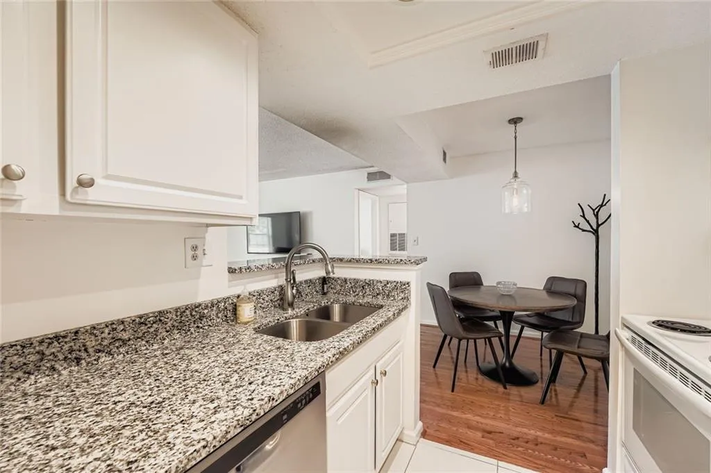 Kitchen with stainless steel dishwasher, white cabinetry, light stone countertops, pendant lighting, and white electric stove