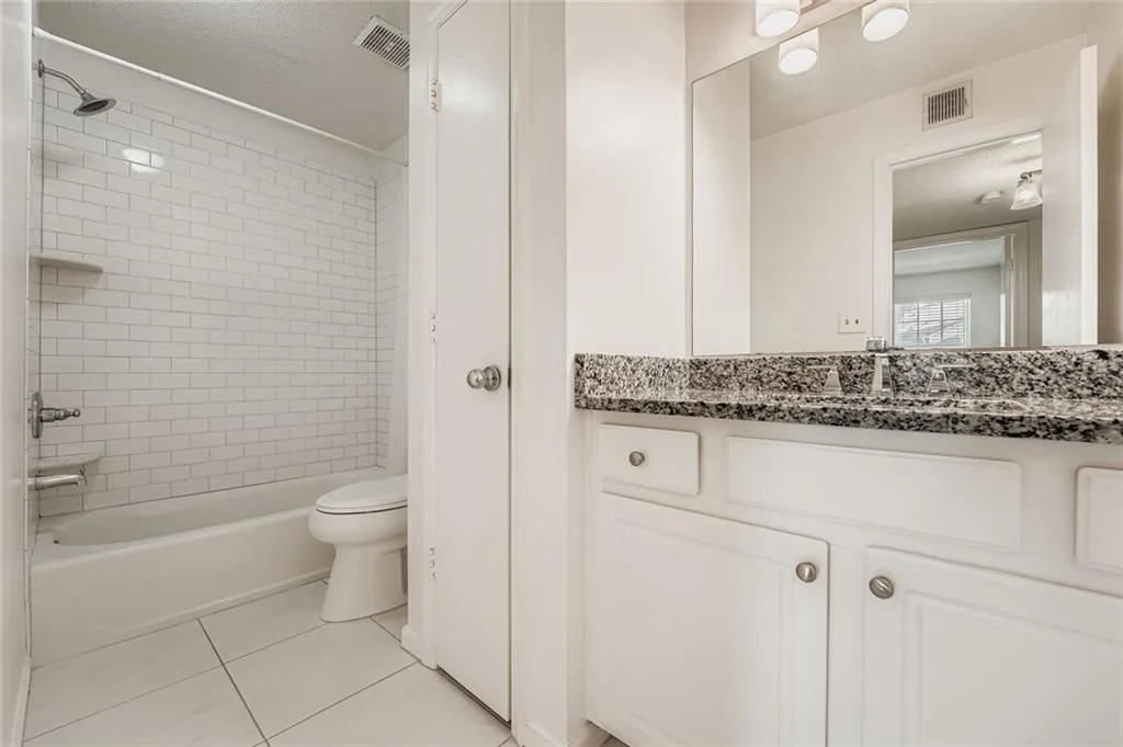 Bathroom featuring tile patterned flooring, vanity, shower / tub combination, and a textured ceiling