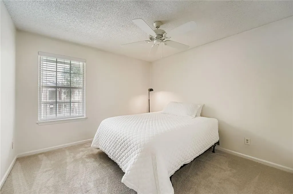 Carpeted bedroom featuring a textured ceiling and a ceiling fan