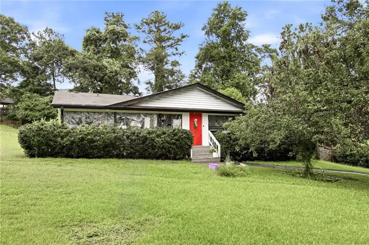 White siding exterior with a red front door, entry stairs, and established front landscaping