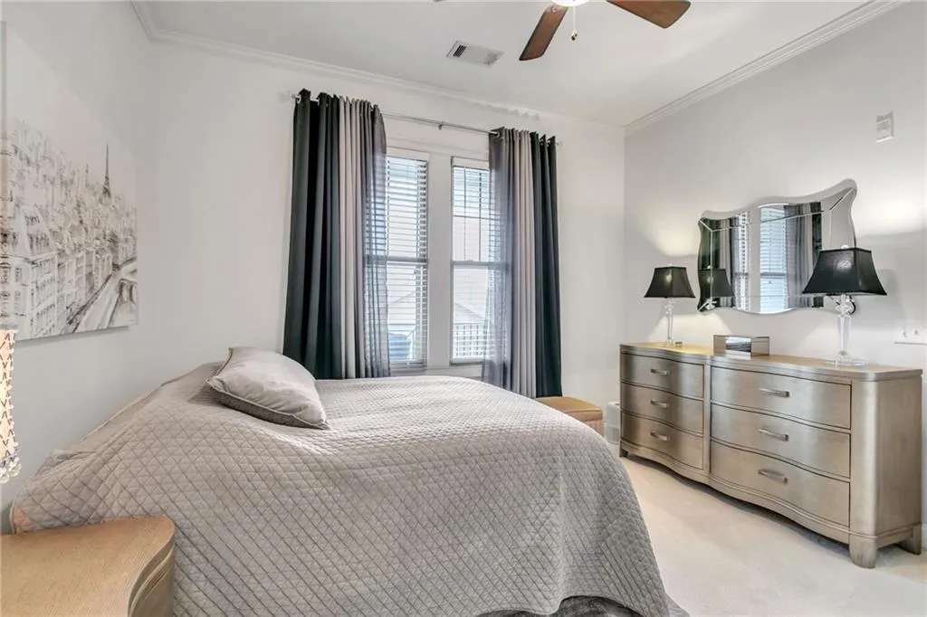 Carpeted bedroom featuring ceiling fan and crown molding