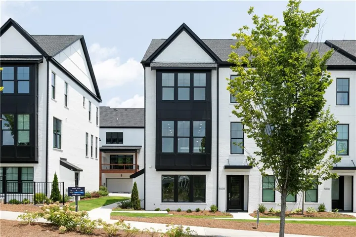 Modern townhome exterior featuring a white brick facade and striking black trim accents