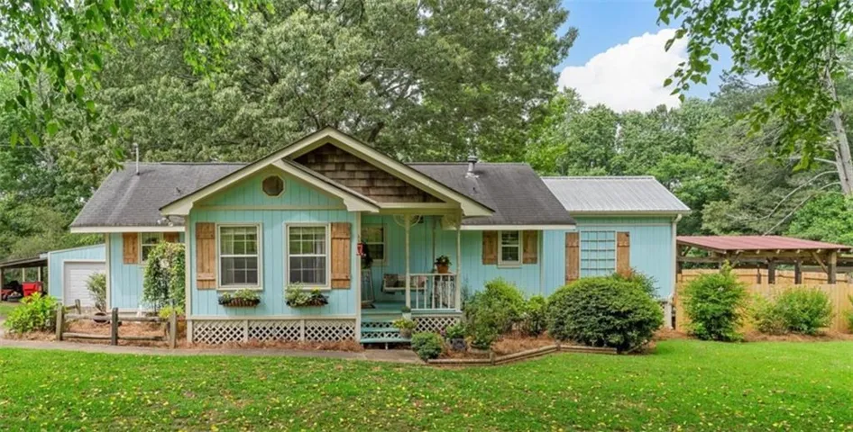 Light blue siding exterior featuring wood window shutters, a covered front porch, and an attached carport