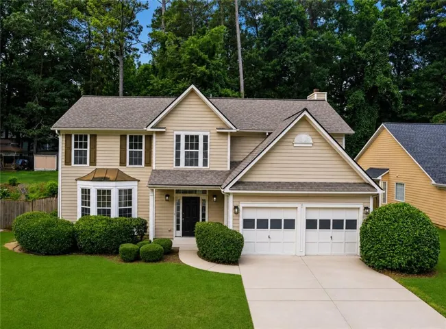 Two-story residence featuring light-toned siding and a prominent two-car garage