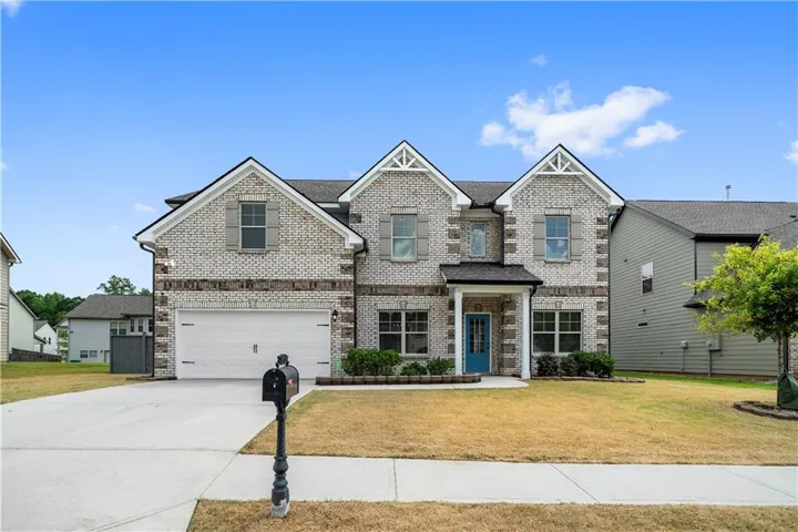 Two-story residence featuring light brick exterior, prominent gables, and a two-car garage