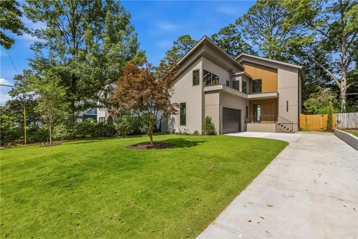 Modern architectural residence featuring multi-toned siding, a two-car garage, and a concrete driveway