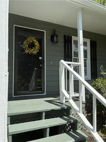 Front entry featuring a full-light storm door, decorative outdoor sconce, and white window shutters