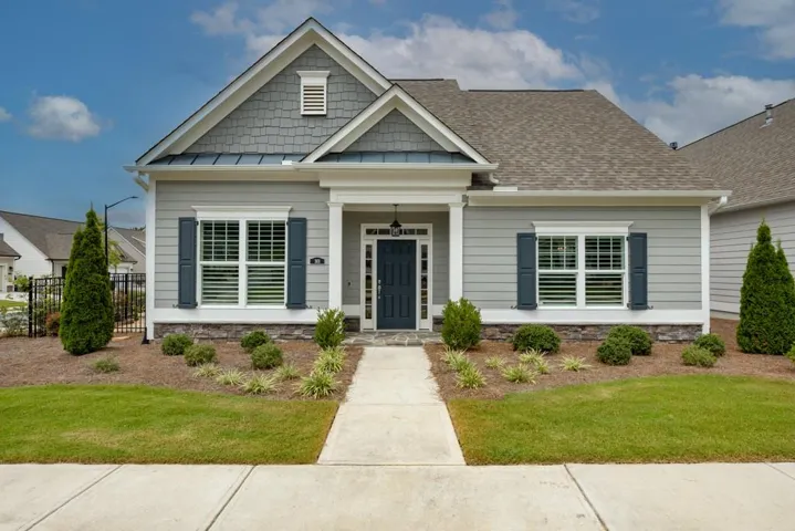 Exterior featuring siding, stone accent base, an asphalt shingle roof, and a concrete pathway