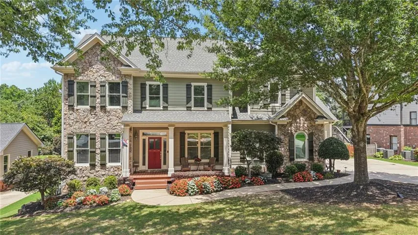 Stone and siding exterior with a prominent red entry door and a covered front porch