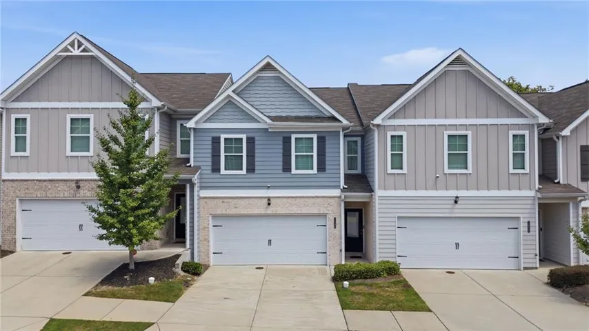 Contemporary townhome exterior featuring brick and siding finishes, gabled rooflines, two-car garage, and multiple windows