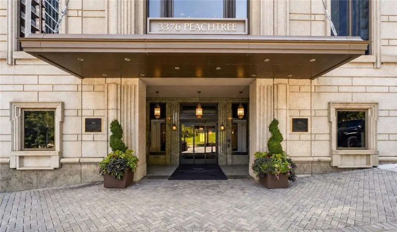 Stone facade with decorative detailing, covered entryway, and a paver driveway