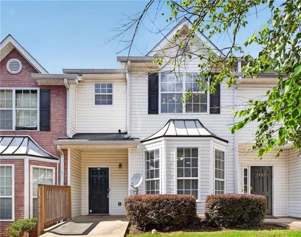 White siding exterior featuring a prominent bay window with black shutters, a black entry door, and a covered porch