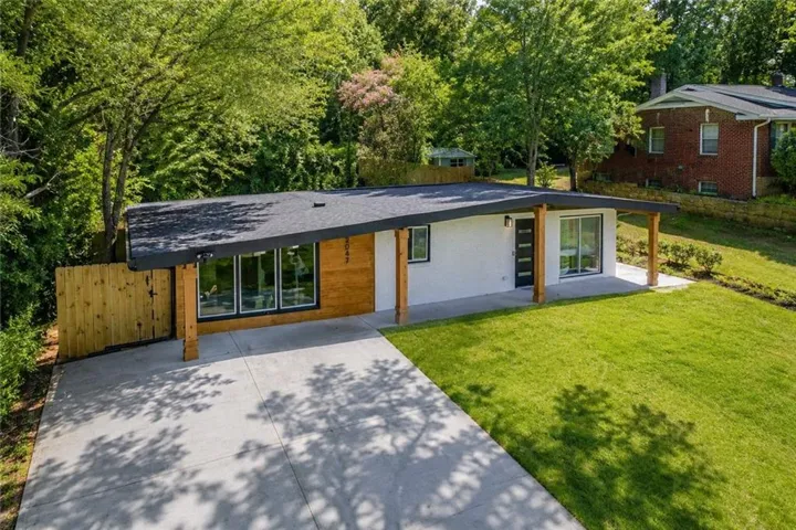 Modern exterior featuring a white facade with natural wood accents, a black shingle roof, and a concrete driveway
