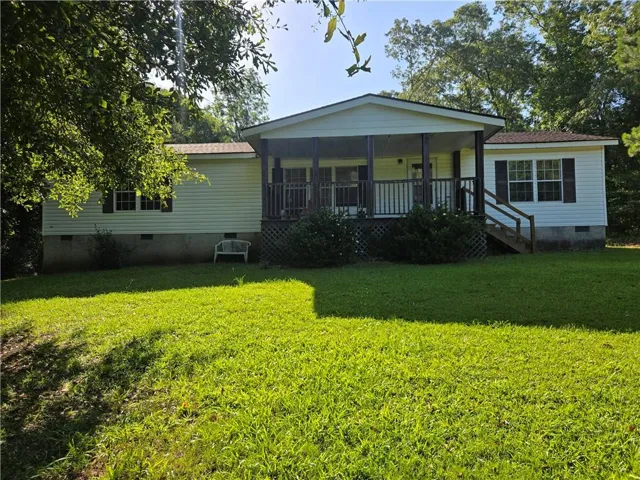 Single-story residence featuring light-colored siding, a covered front porch with dark wood railings, and a side entrance with wood steps