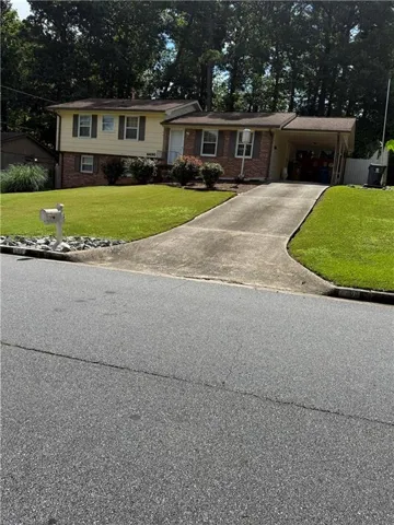 Split-level residence featuring a brick and siding facade, covered carport, and a concrete driveway