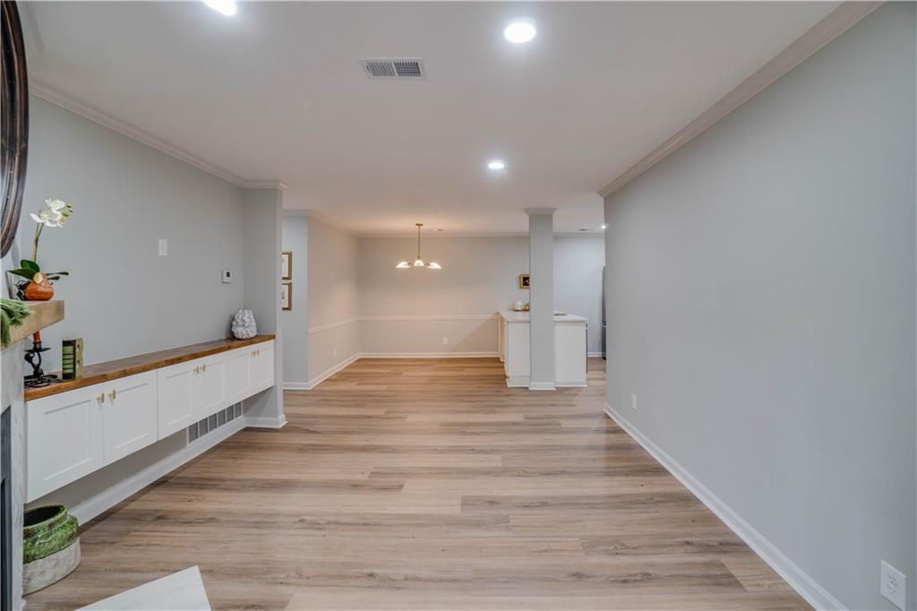 Hallway with ornamental molding, a chandelier, and light hardwood / wood-style flooring