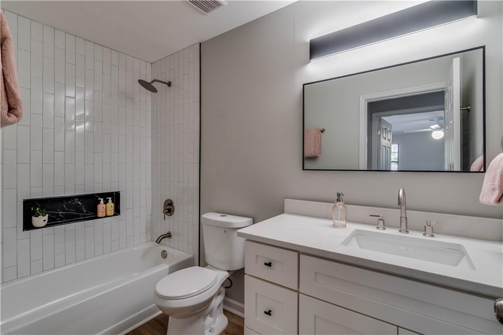 Full bathroom featuring vanity, tiled shower / bath, toilet, ceiling fan, and hardwood / wood-style floors