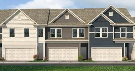 Three-unit multi-family residence with individual garage doors, multiple window configurations, and varied exterior siding