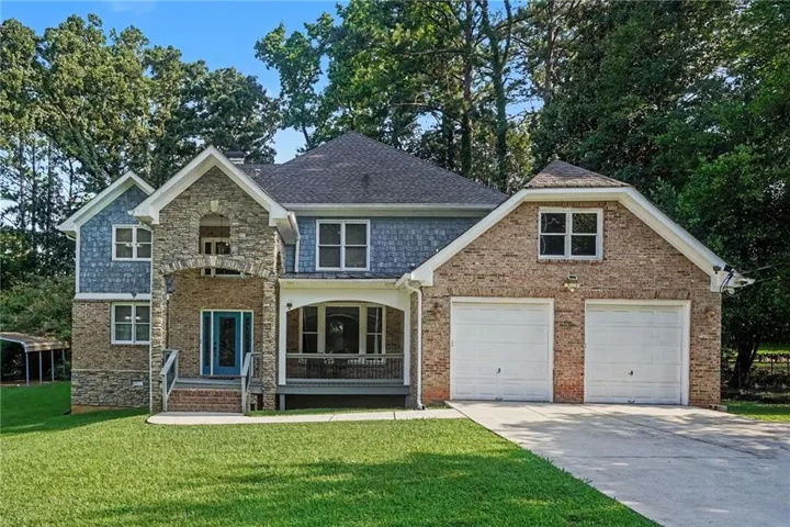 Stunning two-story brick and stone Colonial featuring a covered front porch, dual two-car garage, and slate-style driveway