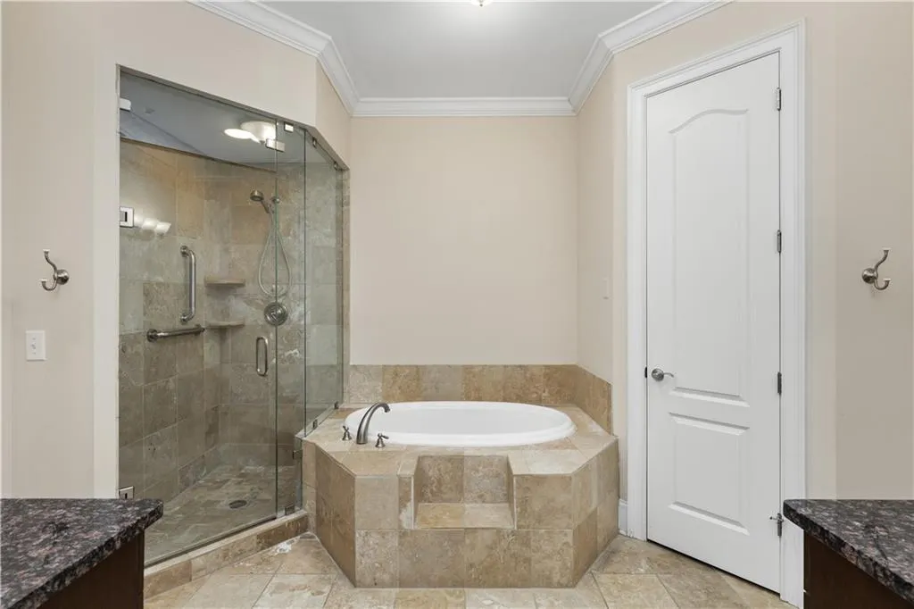 This is the marble spa-like Primary Bathroom with a glass walled shower and bathtub which can be used as either a soaking tub or a therapeutic jetted Jacuzzi.  The door opens to the private water closet.  There are two matching vanities.