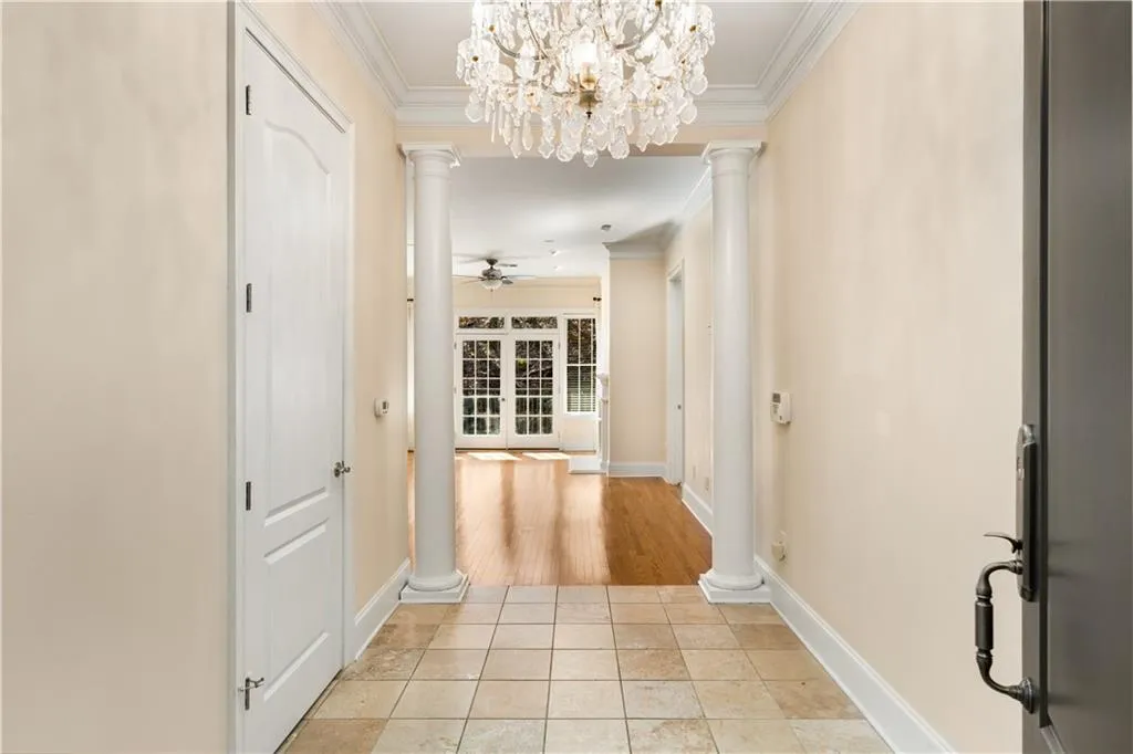 Present view of the welcoming marble Entry Foyer. The beautiful chandelier complements the wonderful moldings, 10 feet ceilings, 8 feet doors and Baldwin Brass hardware.  The alarm system control box is on the wall near the column on the right side.