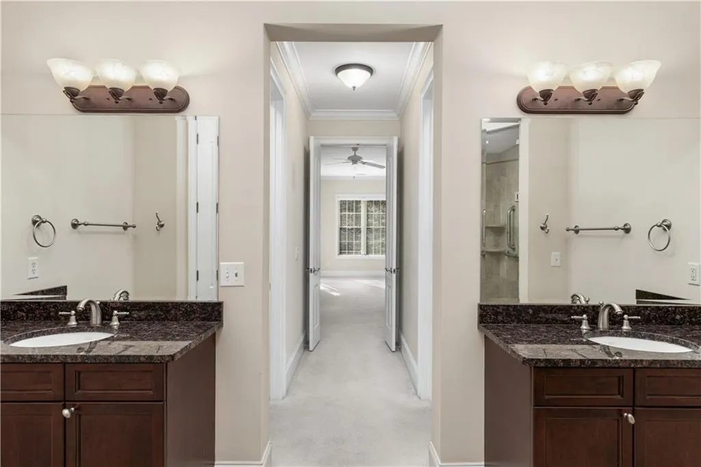 This view includes both granite vanities and the hallway which has walk-in closets on both sides.