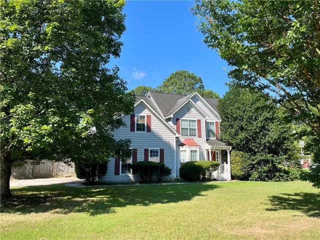 Two-story traditional residence featuring grey siding with red shutters, a prominent front gable, and a covered front entry