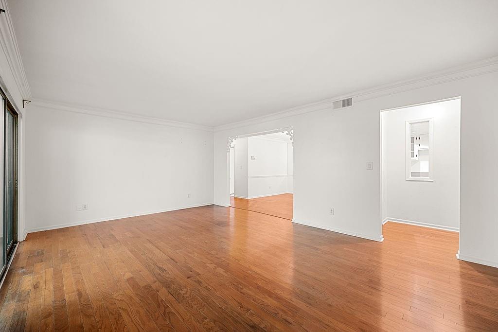 Unfurnished room with crown molding and light wood-type flooring Unfurnished room with crown molding and light wood-type flooring