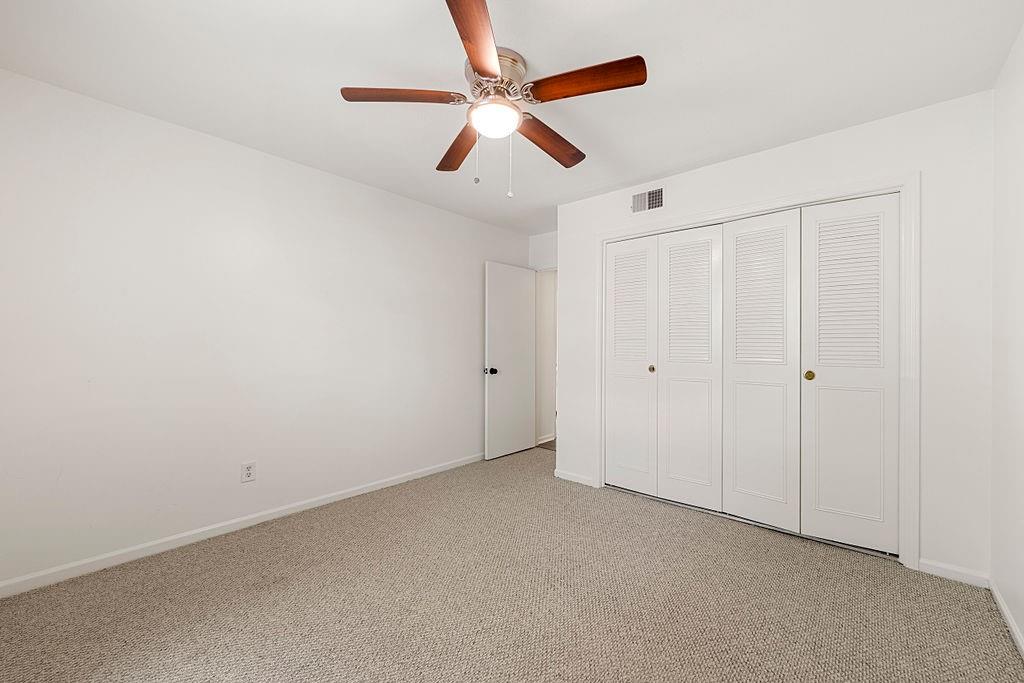 Unfurnished bedroom with a closet, light carpet, and ceiling fan Unfurnished bedroom with a closet, light carpet, and ceiling fan
