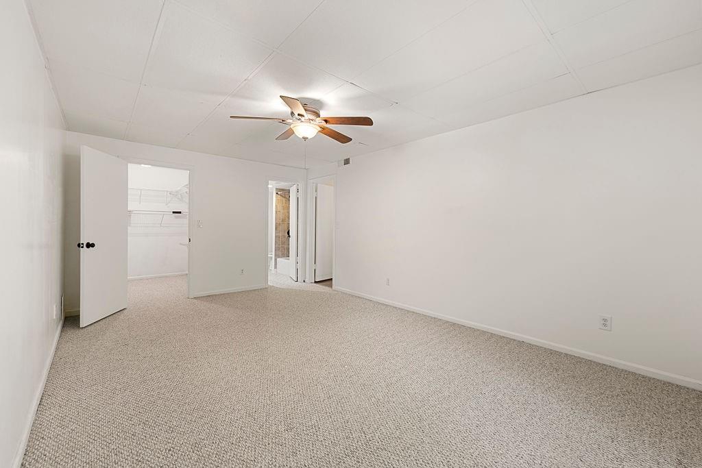 Carpeted empty room featuring ceiling fan Carpeted empty room featuring ceiling fan