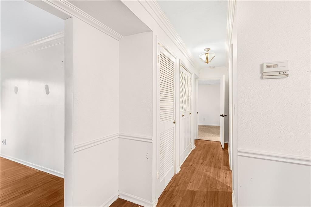 Corridor with crown molding and dark hardwood / wood-style flooring Corridor with crown molding and dark hardwood / wood-style flooring